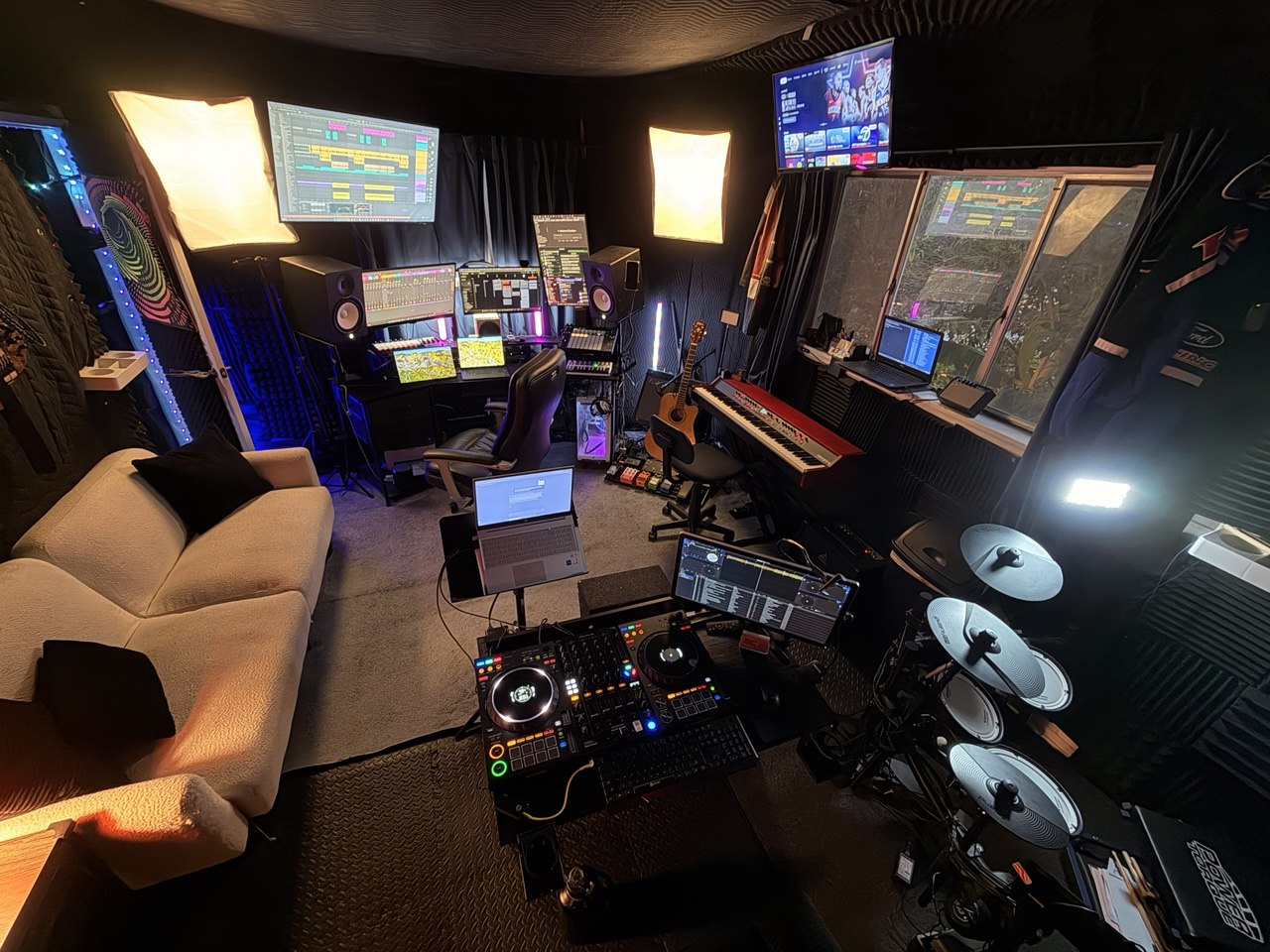 The studio: monitors, keys, drum kit, decks and a couch in one room